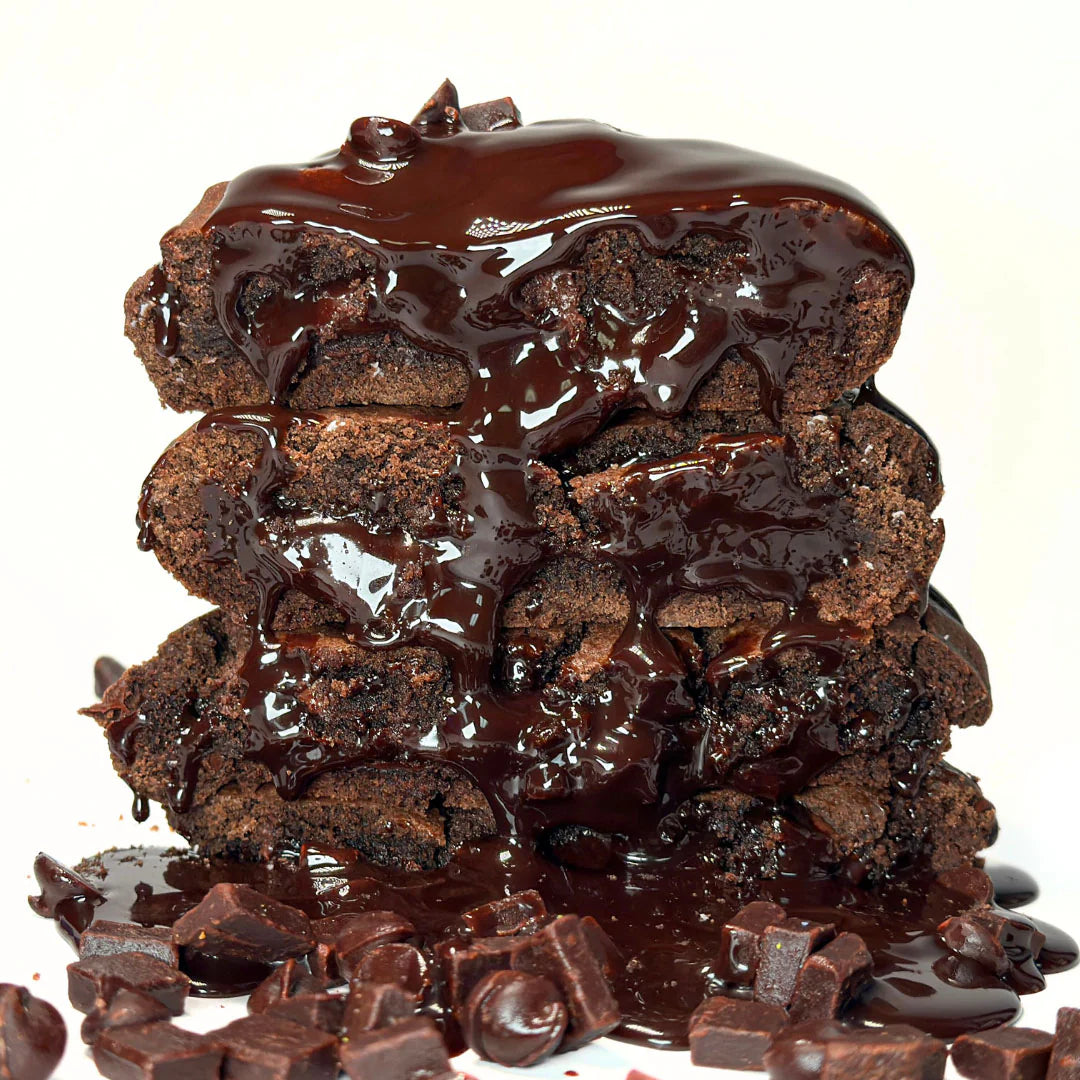 Four chocolate cookies stacked on top of each other with chocolate sauce dripping down