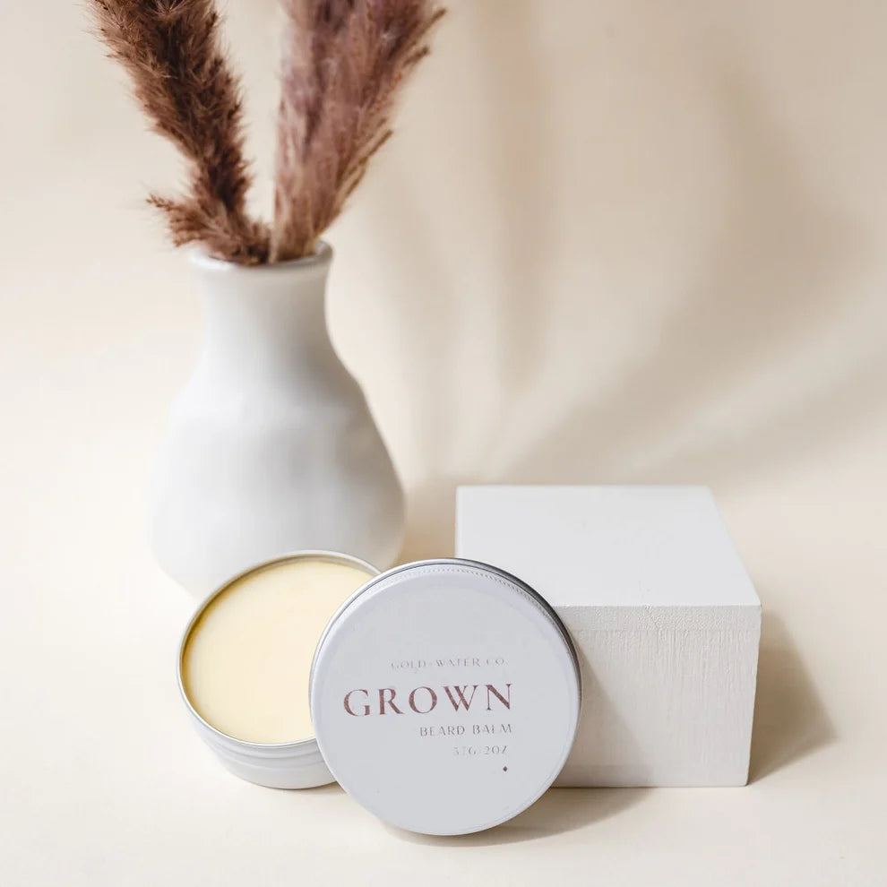 beard balm tin featured in front of vase and box