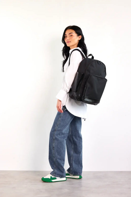 model with black backpack over shoulder