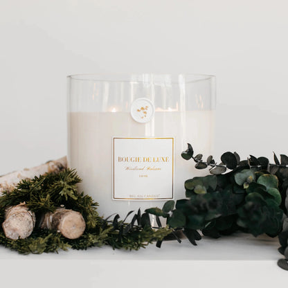 large white candle displayed with eucalyptus and greens 