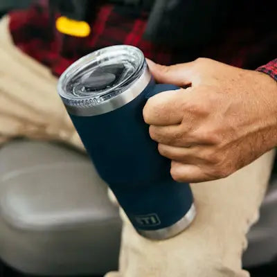 person holding a navy blue insulated mug with top