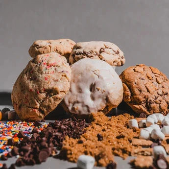 Assortment of cookies stacked on a surface with sweet ingredients spread in front