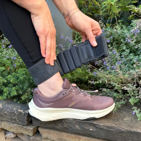 person with leg on ledge putting on ankle weights