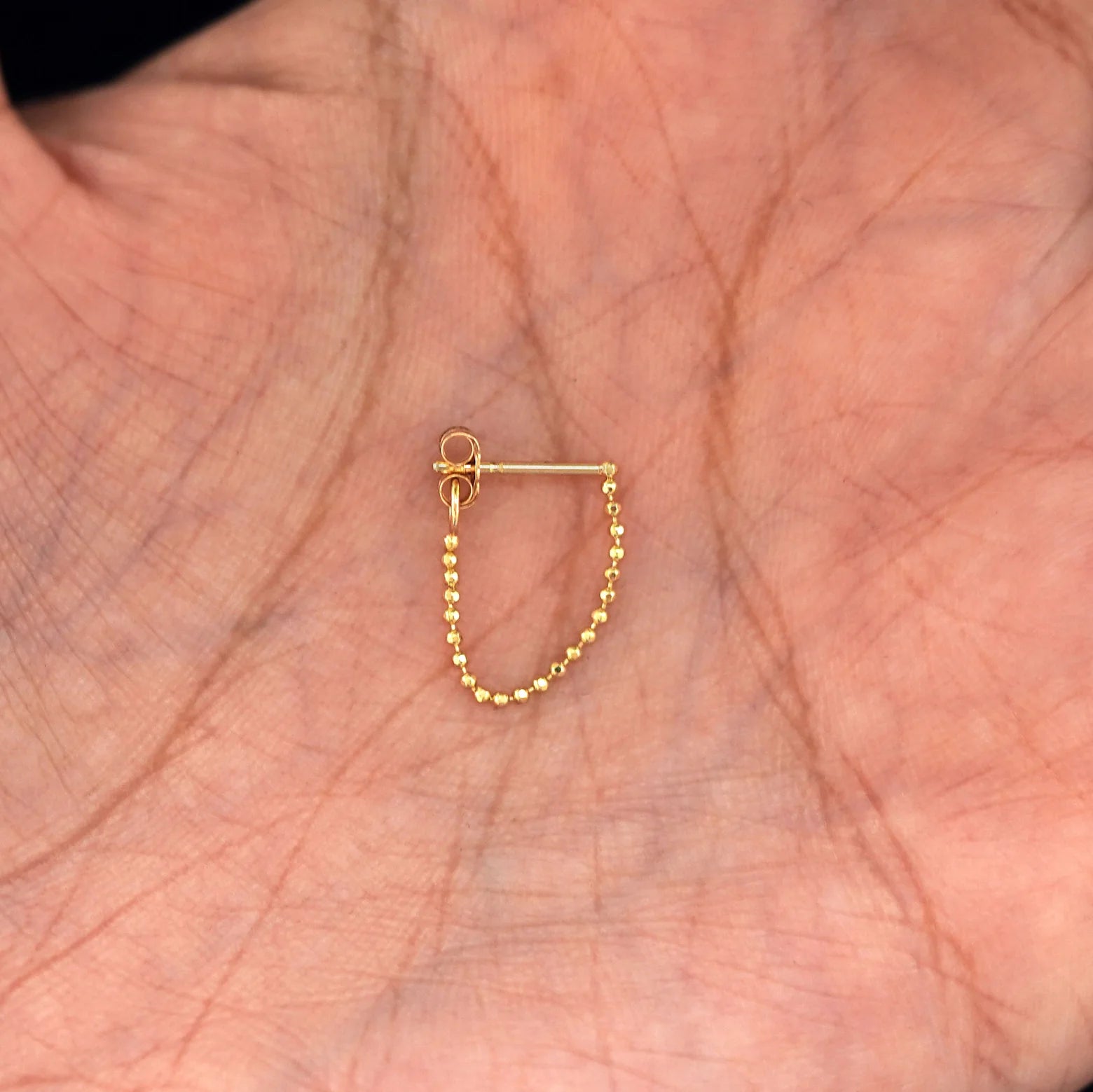 stud and chain earring on display in hand