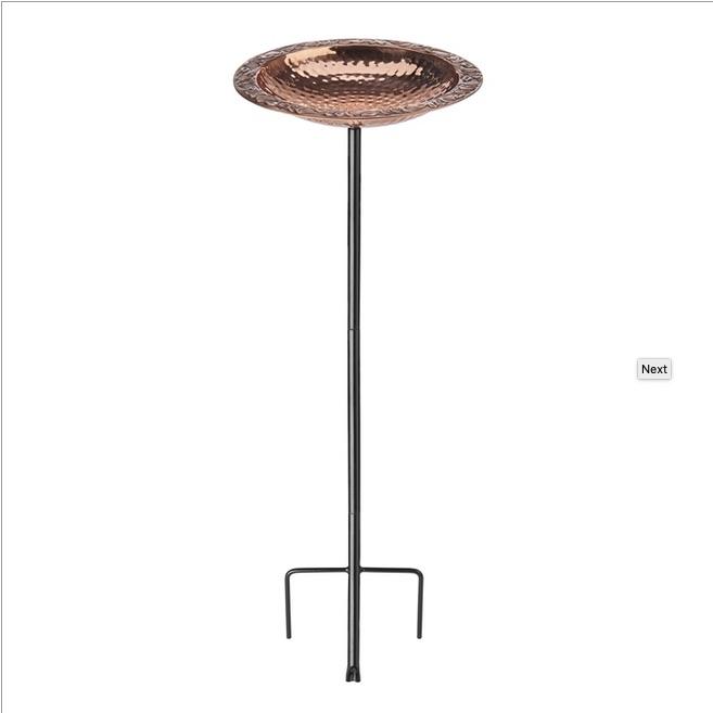 copper bird bath on top of black steel stake