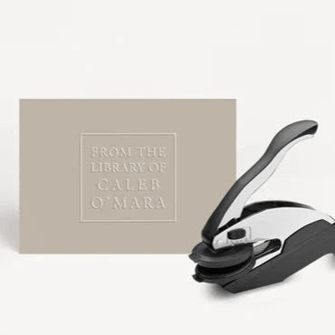 embossed card that says from the library of caleb omara with embosser next to it