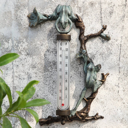 metal frogs along flowered branches showcasing glass thermometer on wall