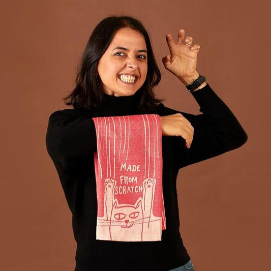 woman holding towel that says made from scratch with her holding up fingers like a cat