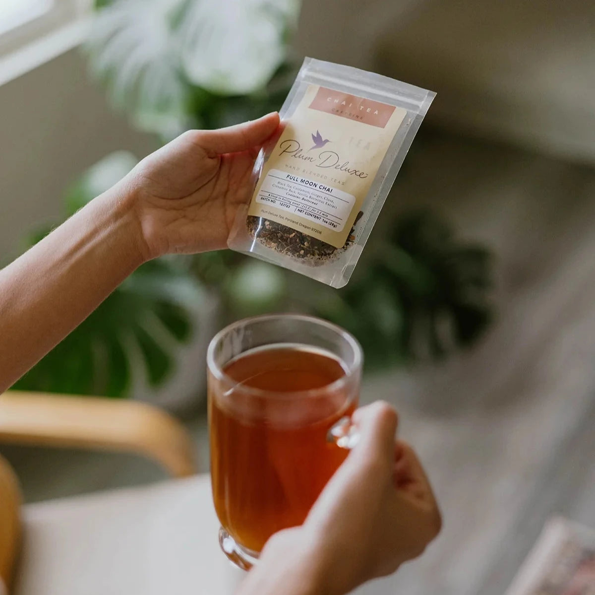 woman holding tea bag with mug of brewed tea